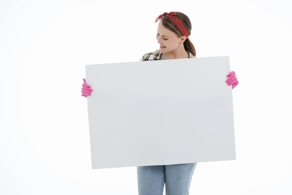 A woman carefully wraps a sofa in protective material while packing boxes in a bright room.